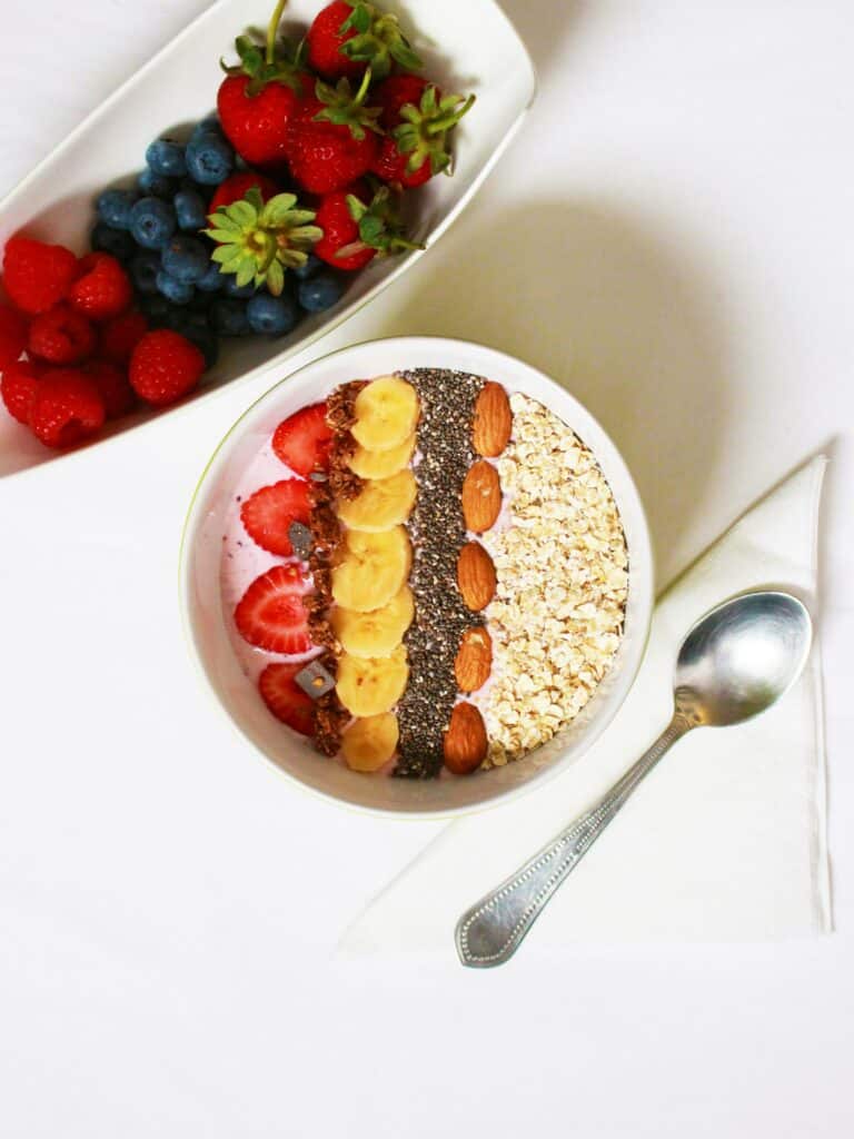 a bowl of high fiber foods such as oats, almonds, chia seeds and berries